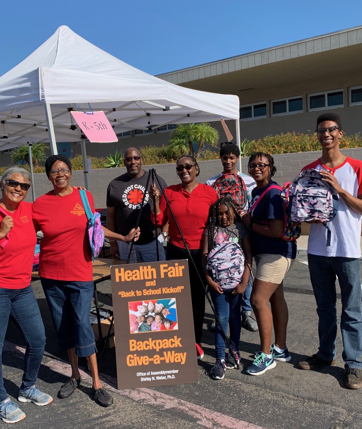Community backpack giveaway under white tent