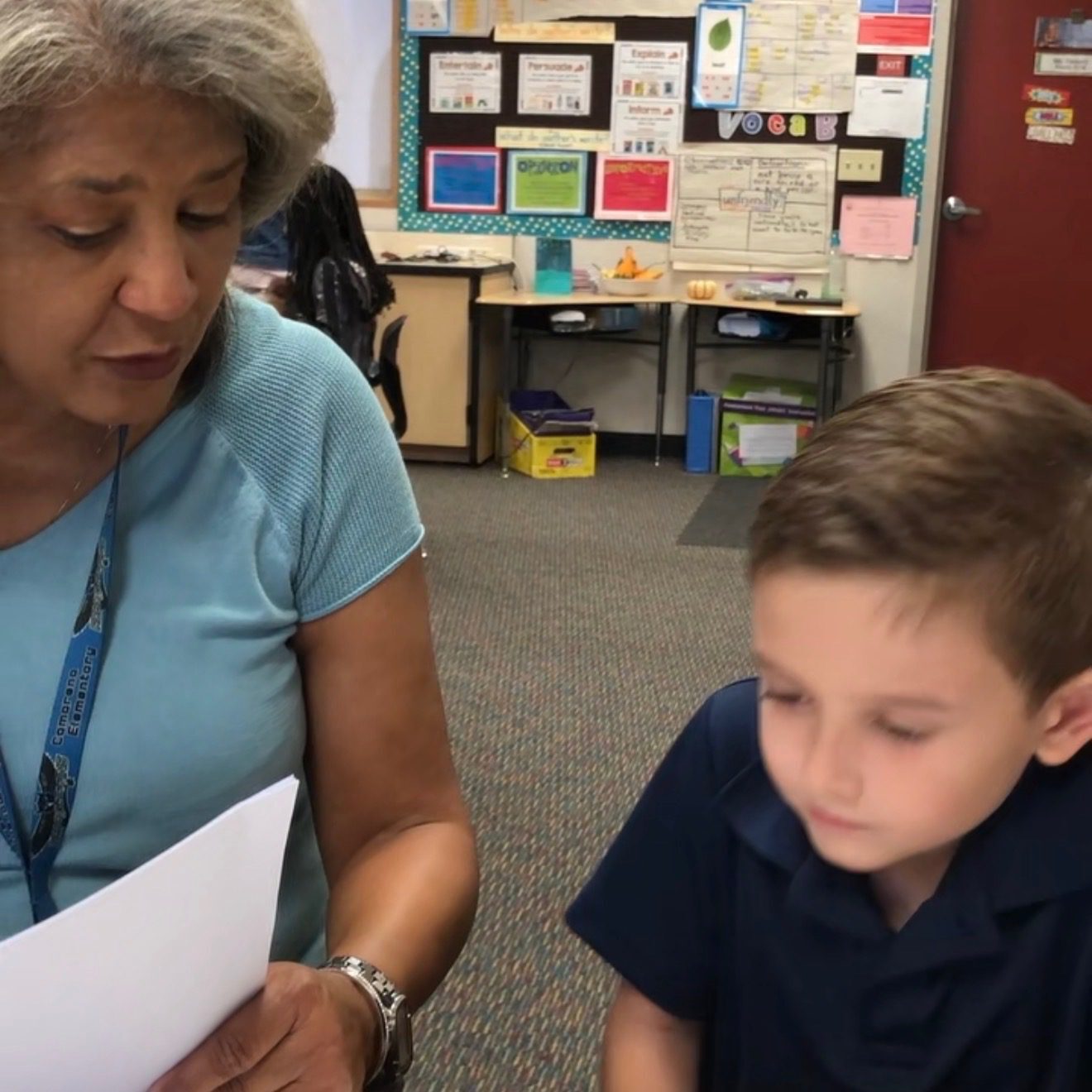 Teacher and student reviewing paper in classroom